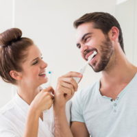 man and woman brushing teeth with electric brushes