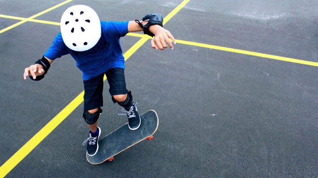 picture of child riding skateboard making tricks with skateboard safety gear