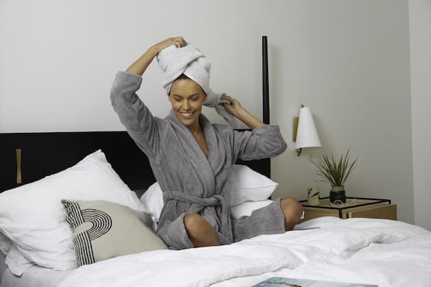 Woman in bathrobe sitting on bed