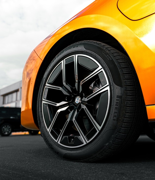 A sleek orange car fitted with stylish auto tires and modern alloy wheels, emphasizing both performance and design.