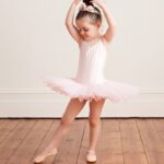 ballerina girl posing wearing white leotards and shoes for ballerina