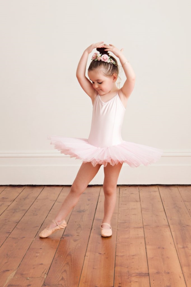 ballerina girl posing wearing white leotards and shoes for ballerina