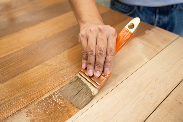 a person using a brush for wood staining