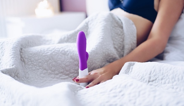 woman in the bed holding dildo sex toy